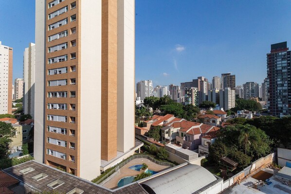 A high-rise building with multiple floors, a rooftop pool, and a cityscape in the background. - Nik Perdizes (São Paulo)