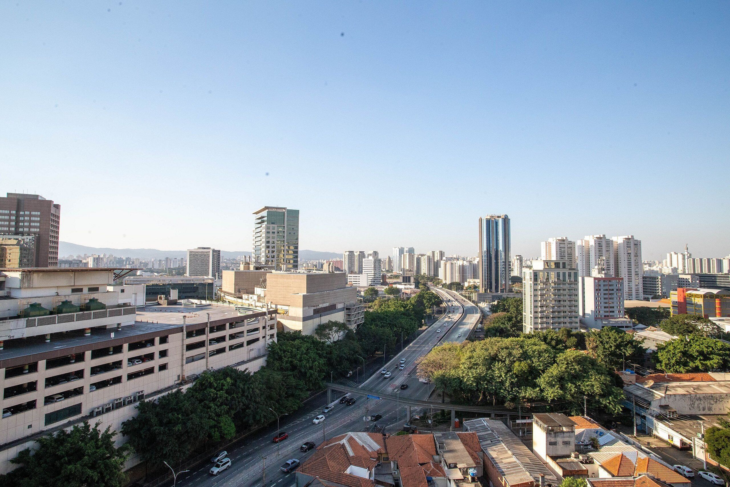 Un paisaje urbano con una estructura de estacionamiento de varios niveles, una autopista y rascacielos.