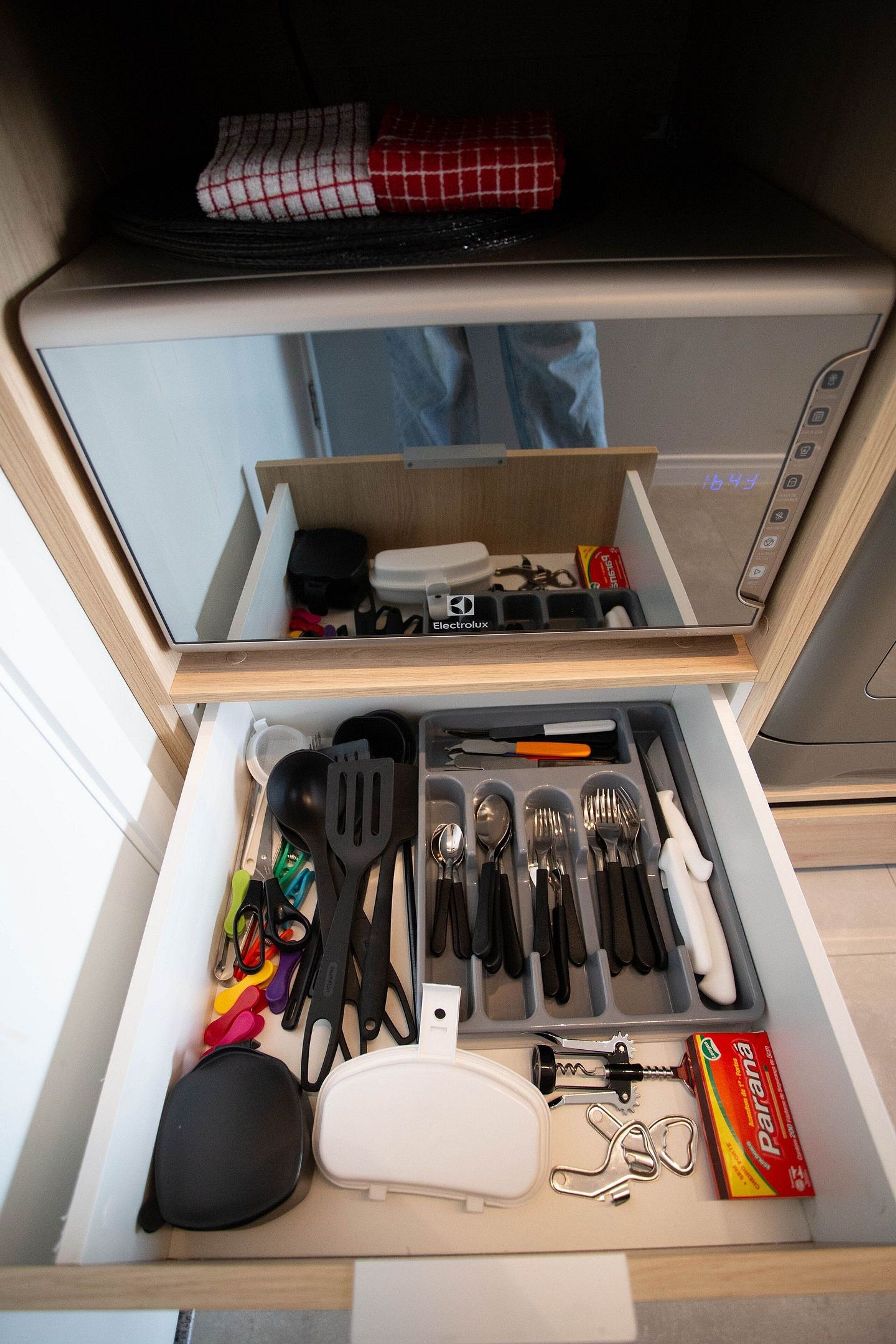 Un cajón de cocina con utensilios, una botella de Parana y un electrodoméstico blanco.