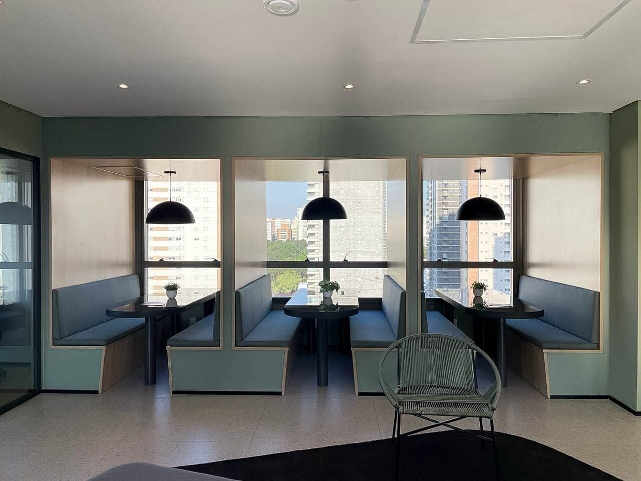 A modern interior with seating areas and large windows offering city views.