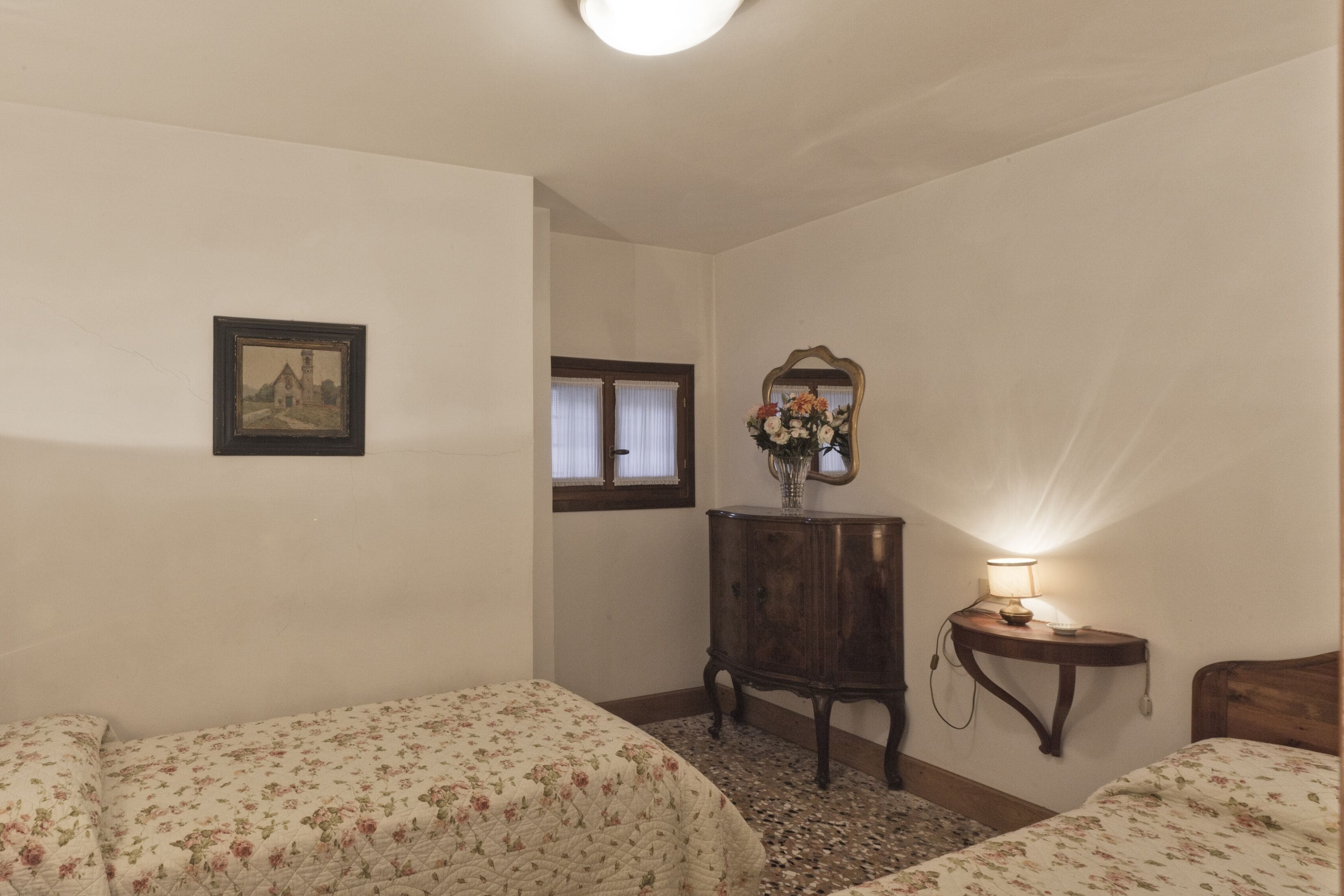 A bedroom with two beds, a wooden dresser, a mirror, and a picture on the wall.