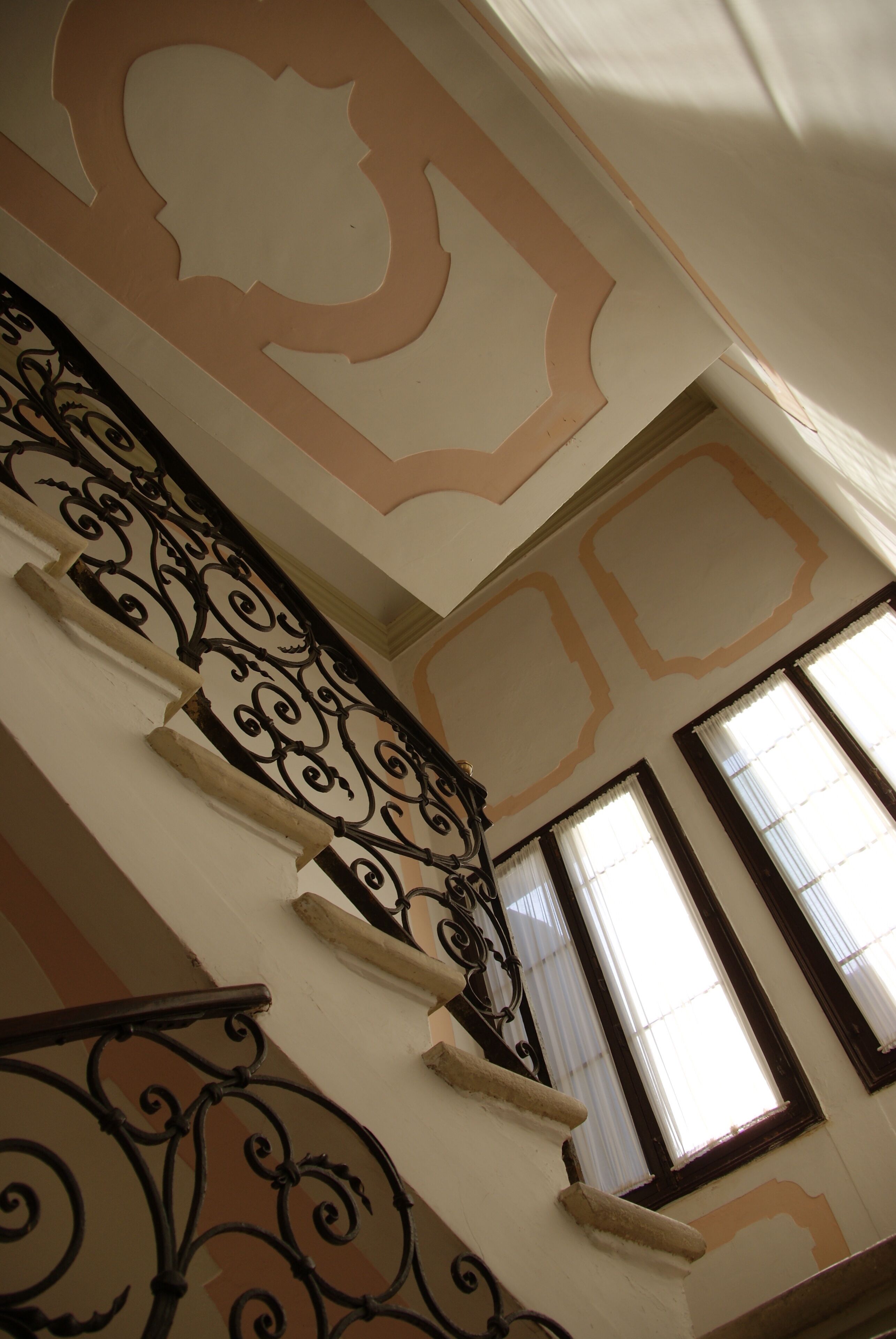A staircase with ornate black railings and a decorative ceiling design.