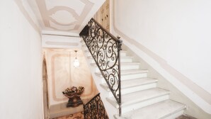 Una scala con ringhiere in metallo nero decorate e gradini bianchi.