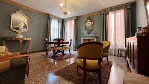 Una stanza con un lampadario, un tavolo da pranzo con sedie, un camino e un grande specchio a parete.