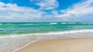 A beach with clear turquoise waters and a sandy shore under a bright blue sky with scattered clouds. - Beachfront Studio, Sleeps 3, Pool (Panama City Beach)