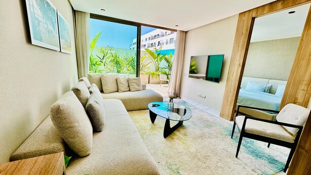 A modern living room with a sofa, coffee table, and a TV mounted on the wall. - Stay'Inn - Anfa Flores (Casablanca)