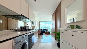 A modern kitchen with a washing machine, a dining area with a sofa, and a large window. - Stay'Inn - Anfa Flores (Casablanca)