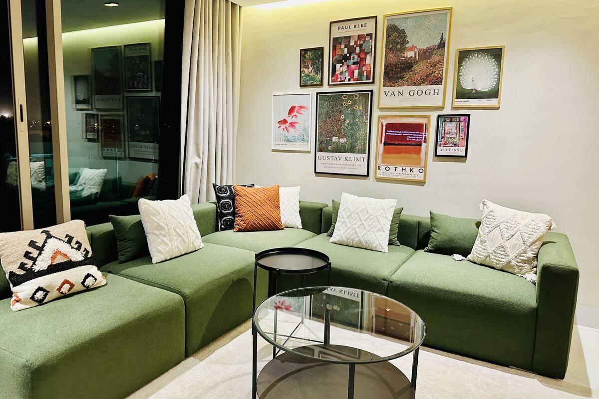 A modern living room with a sectional sofa, a glass coffee table, and artwork on the wall.
