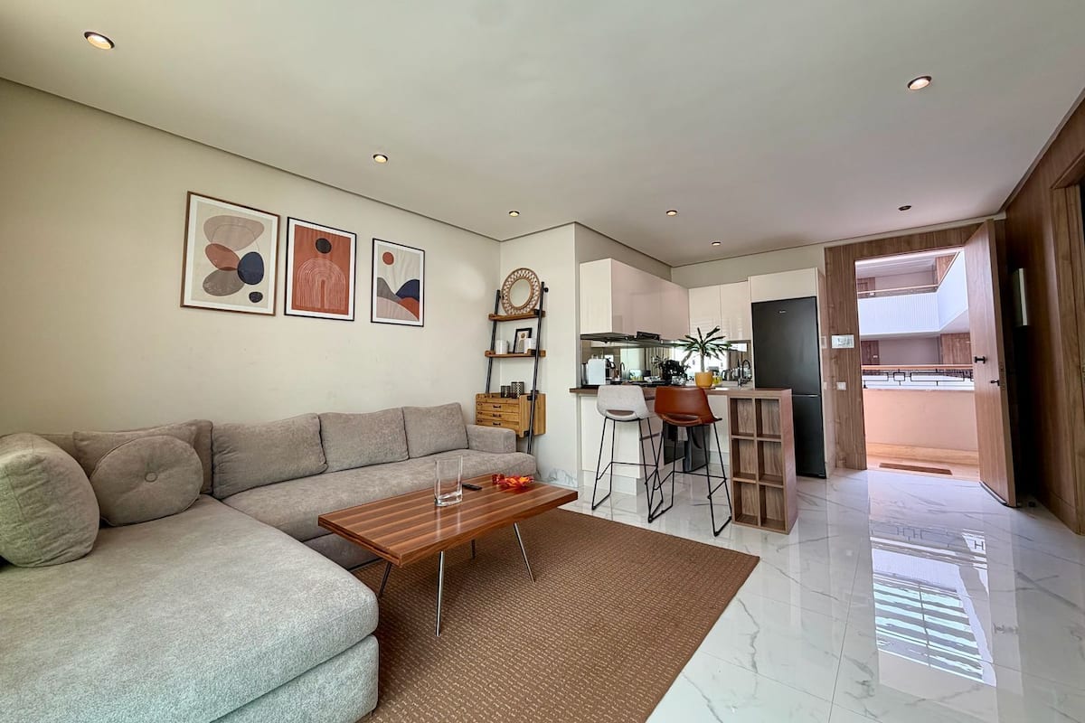 A modern living room with a sofa, coffee table, and artwork on the wall.