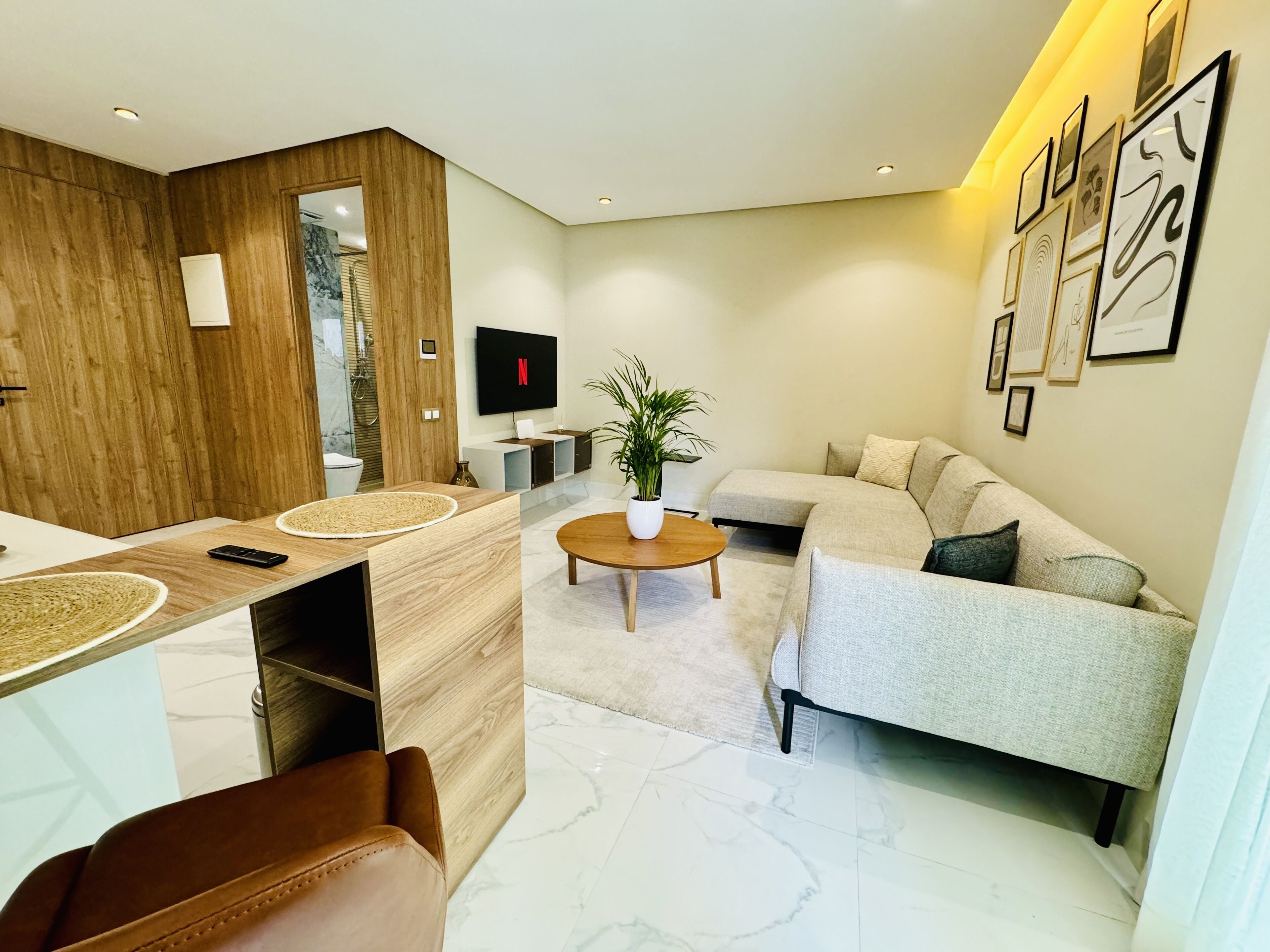 A modern living room with a sofa, coffee table, and a TV mounted on the wall.