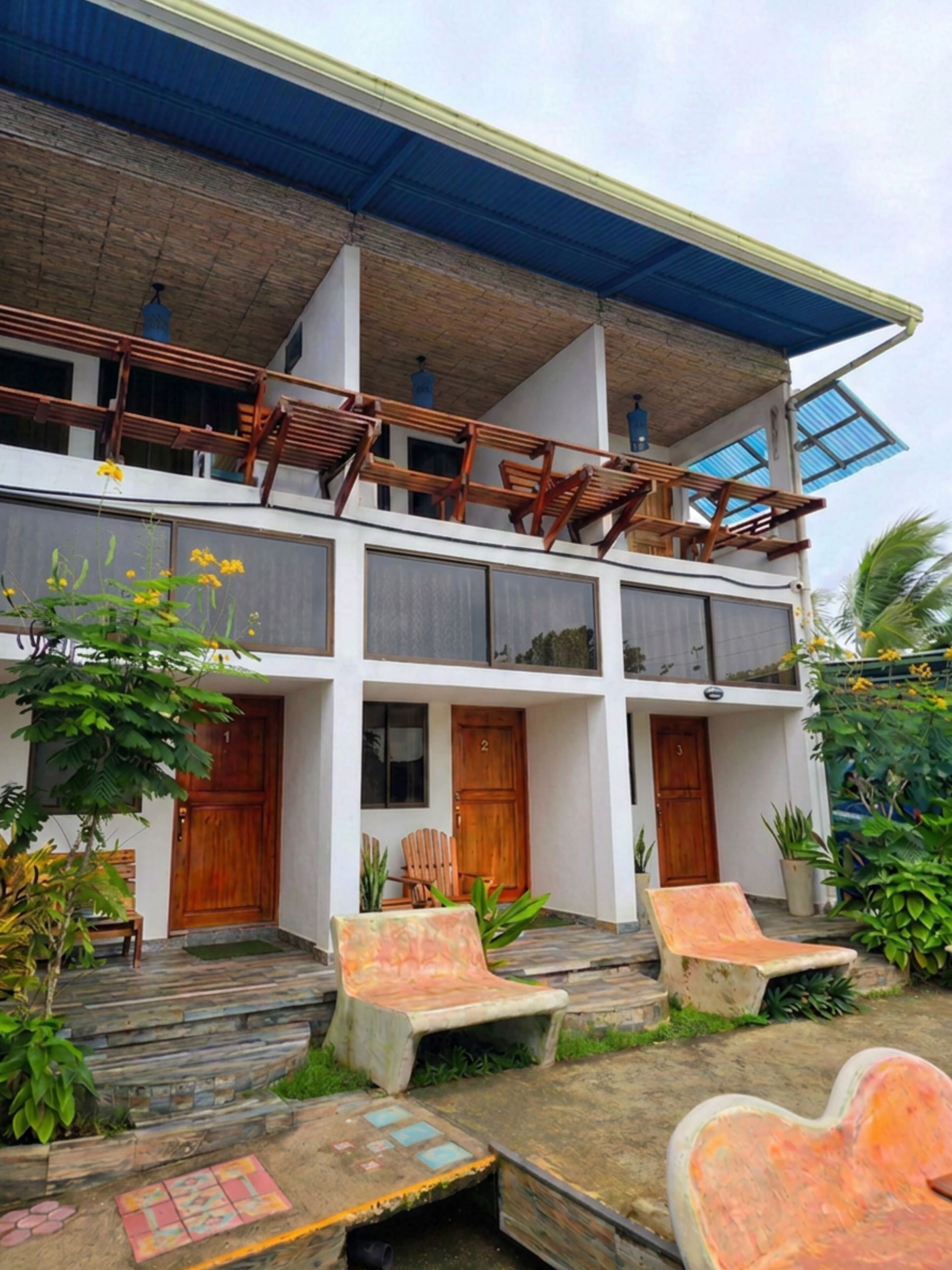 A two-story building with a balcony, wooden doors, and outdoor seating.