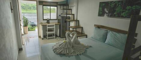 A hotel room with a bed, a desk, and a view of a body of water.