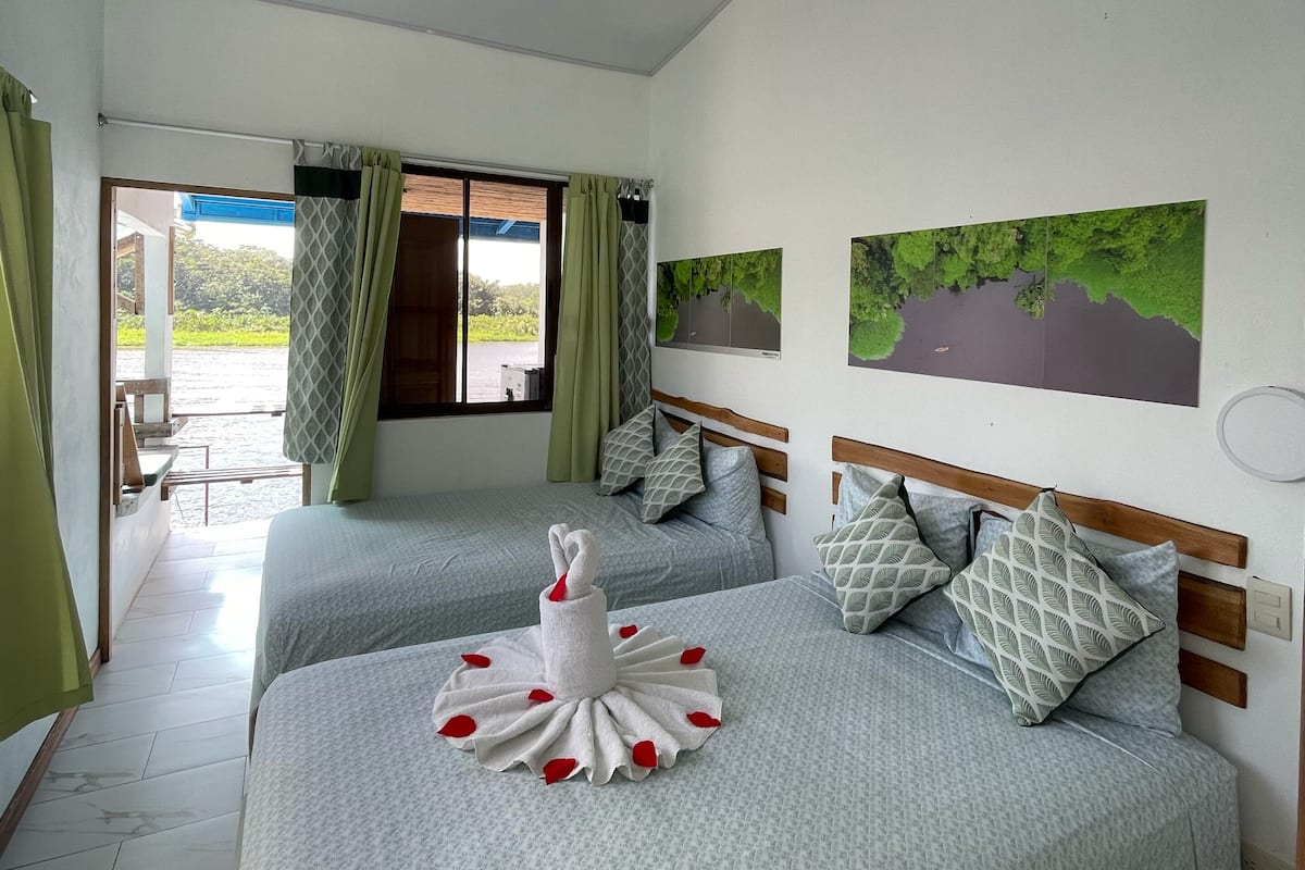 A hotel room with two beds, a view of the outdoors, and a ceiling with a circular light fixture.