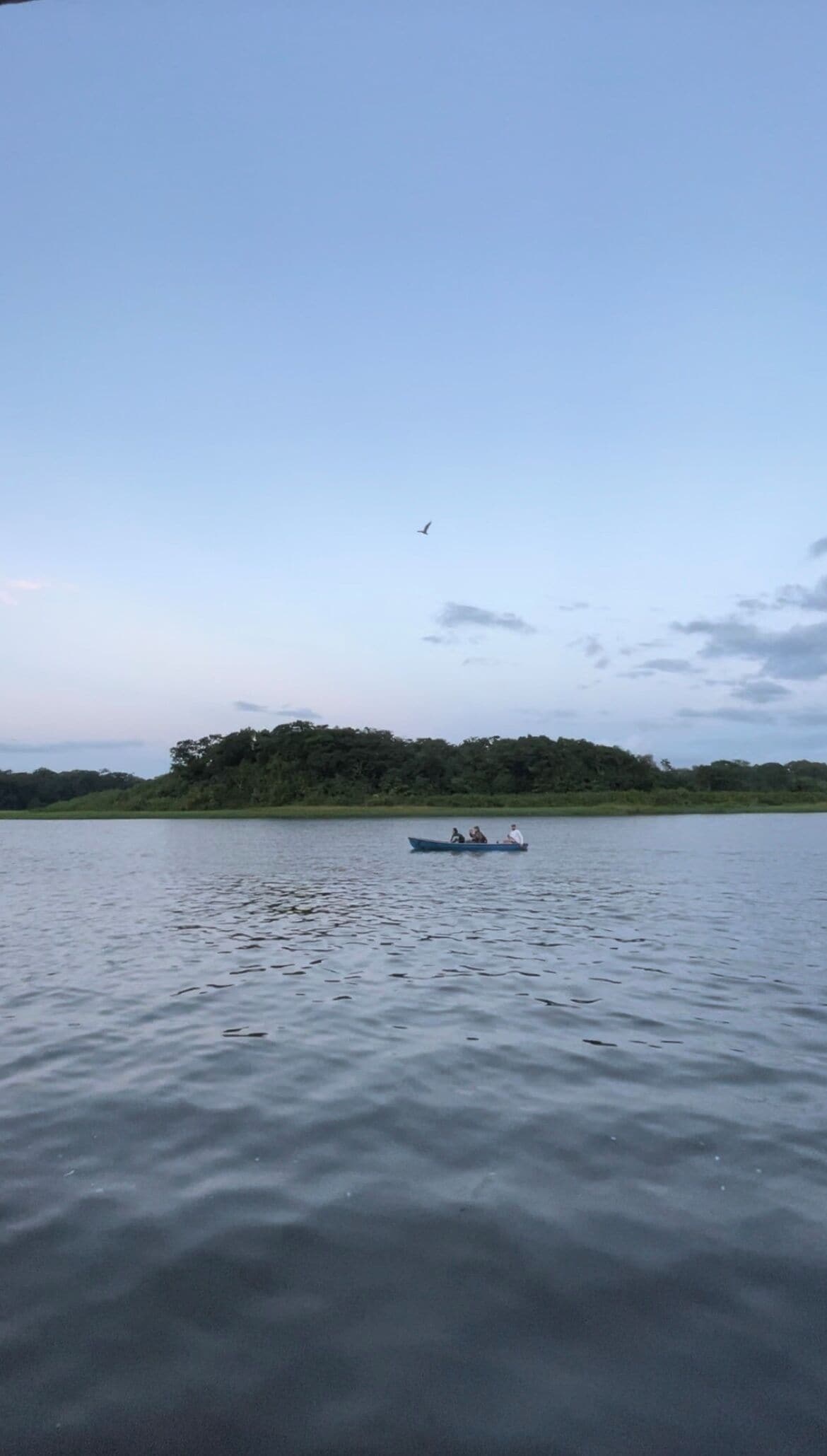 A calm lake with a small boat carrying three people.