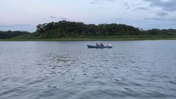 Um lago calmo com um pequeno barco transportando três pessoas.