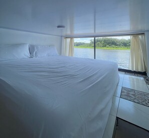Un grand lit dans une chambre avec vue sur une rivière.