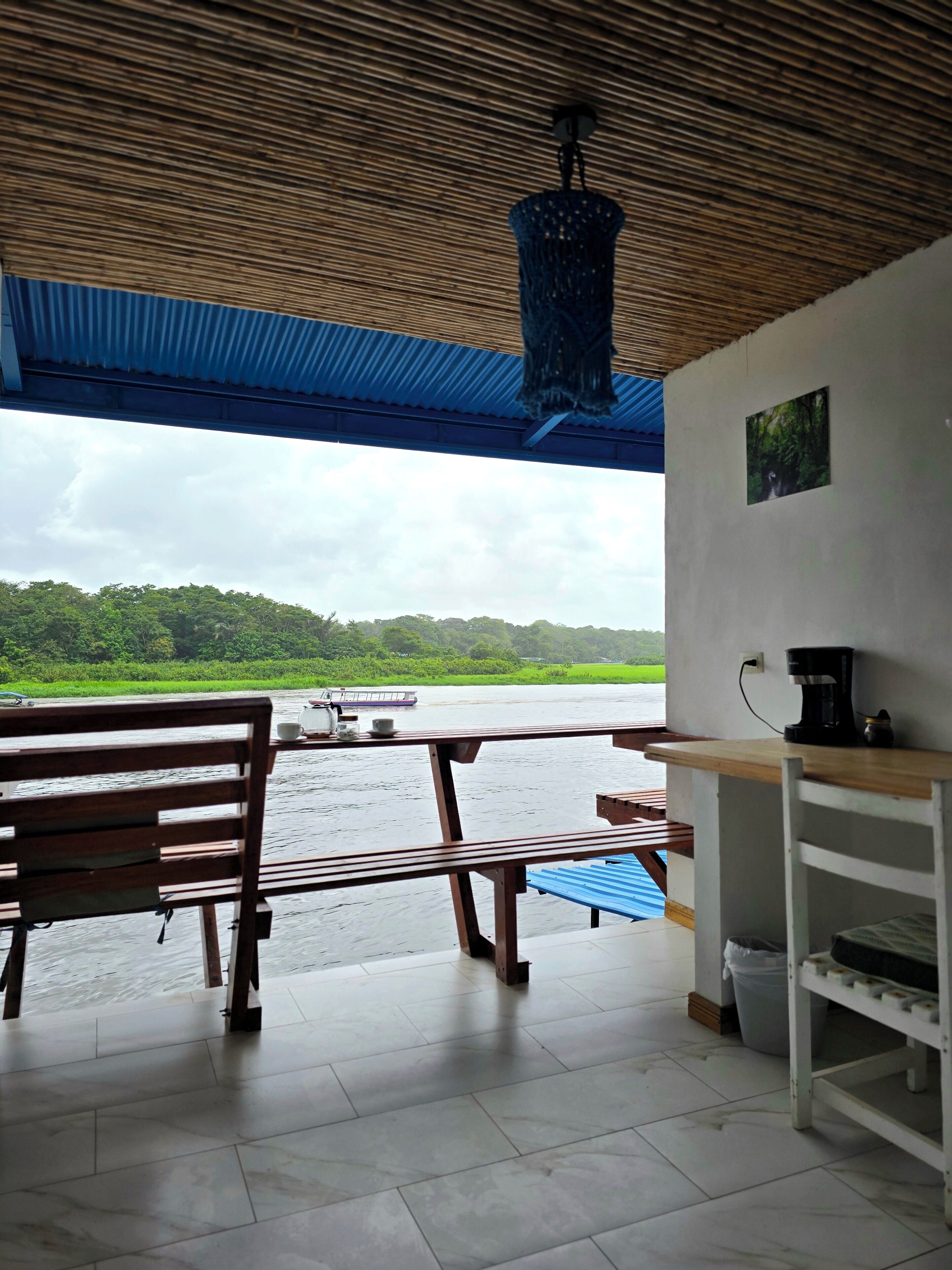 A covered outdoor seating area with a view of a river and greenery.