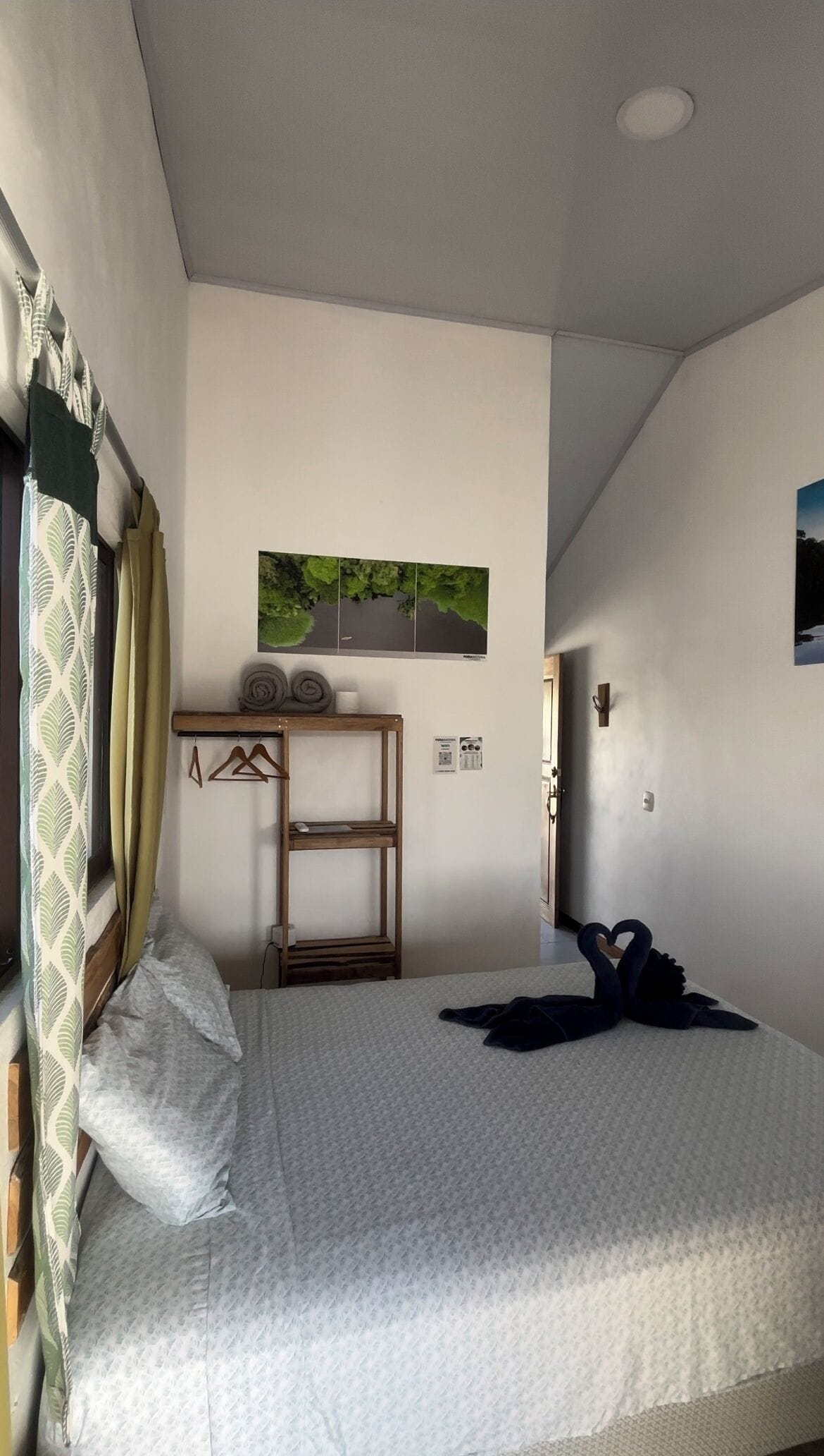 Un dormitorio con una cama, un escritorio de madera, un cuadro en la pared y una puerta.
