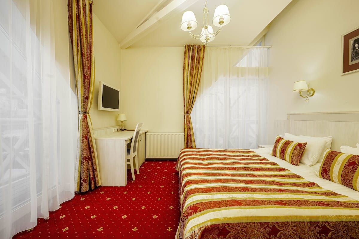A hotel room with a large bed, a desk, and a chair.