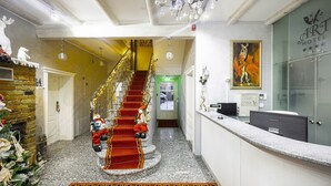 Un lobby de hotel con una imponente escalera, un mostrador de recepción y un árbol de Navidad.