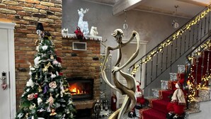 Una sala de estar decorada con chimenea, un árbol de Navidad y una escalera adornada festivamente.