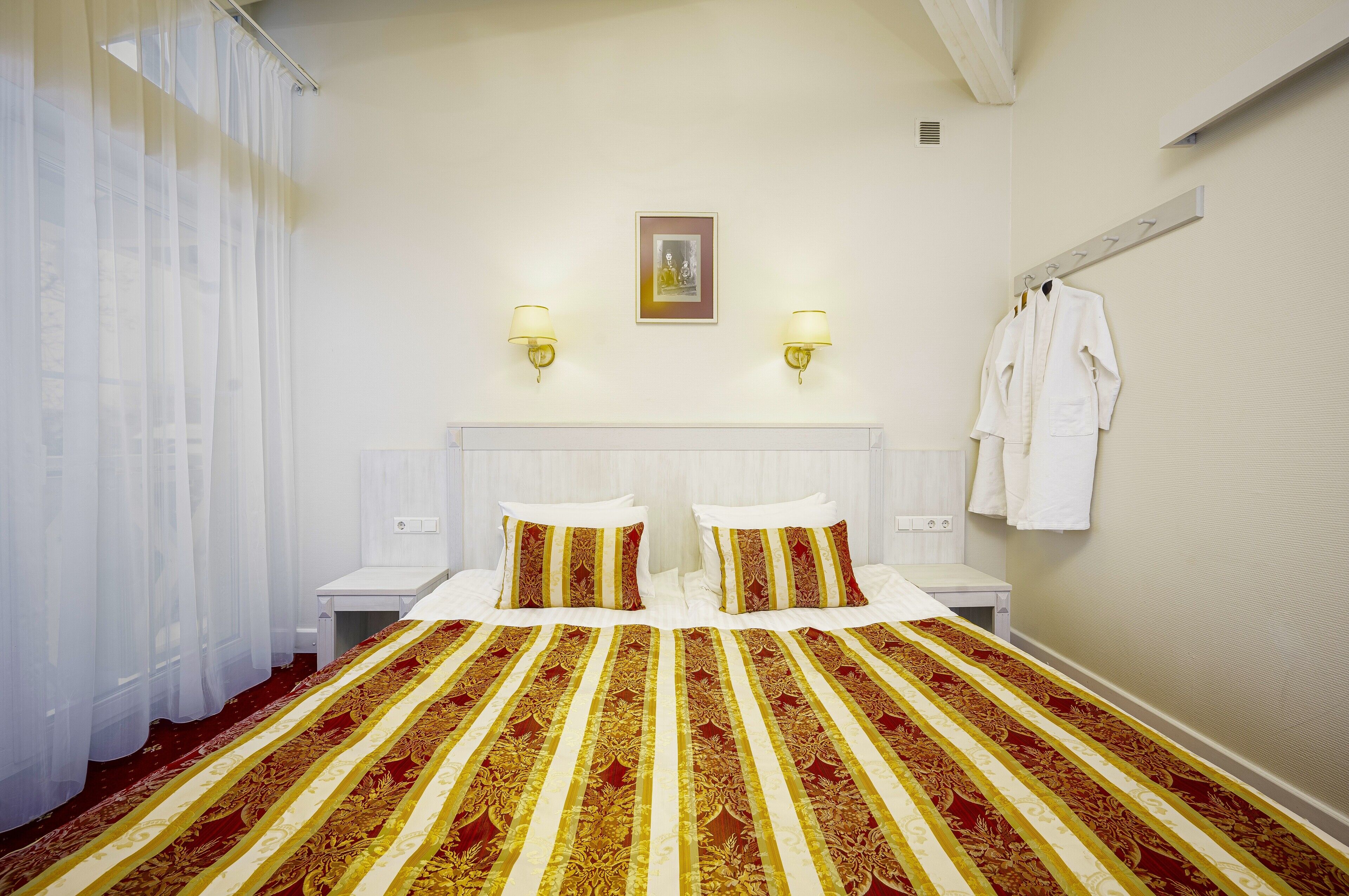 Habitación de hotel con una cama grande, dos mesitas de noche, un cabecero y un perchero para toallas en la pared.