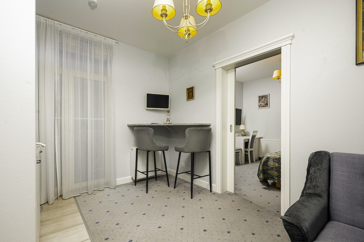 A compact room with a desk, two chairs, a television, and a bed.