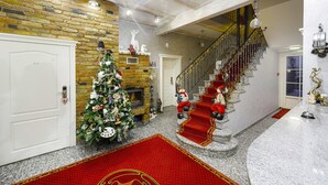 Una imponente escalera con alfombra roja, un árbol de Navidad y una chimenea.