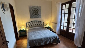 Un dormitorio con cama, dos mesitas de noche, un adorno en la pared y una ventana con cortinas.