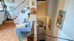 Una escalera con barandilla de madera lleva a un rellano con un sofá azul y una cesta de mimbre.