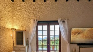 Un comedor con mesa y sillas, un televisor en la pared y vistas a través de una puerta.