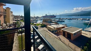 Un puerto deportivo con barcos, un gran barco y edificios al fondo.