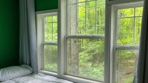 A room with a bed against a wall with two windows.