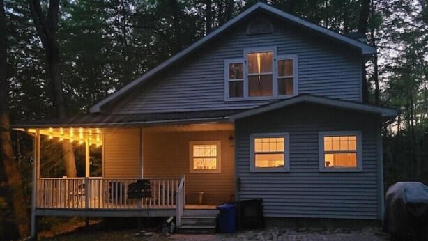 A two-story house with a porch, a small deck, and a covered area.