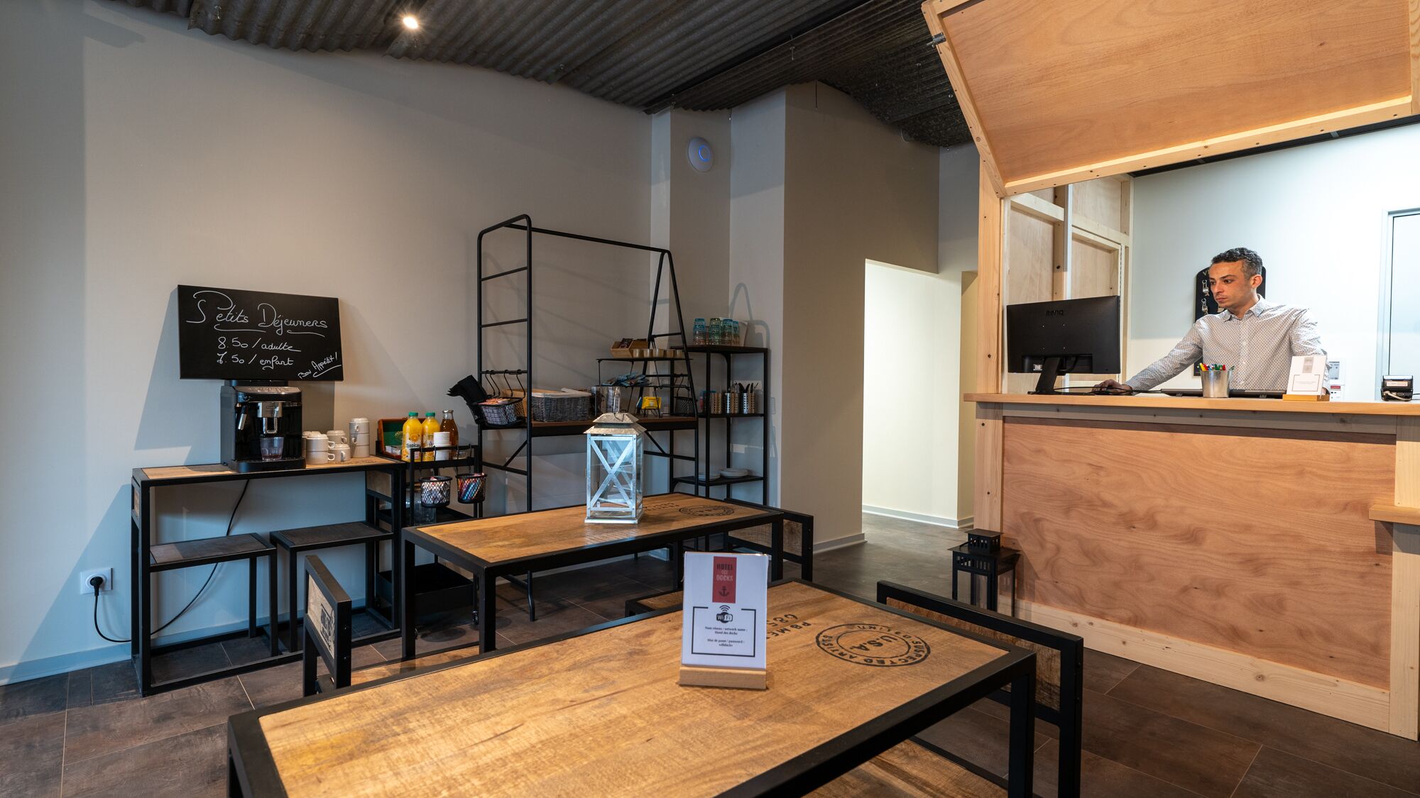 Un café con mostrador de madera, mesas y una pizarra con el menú.