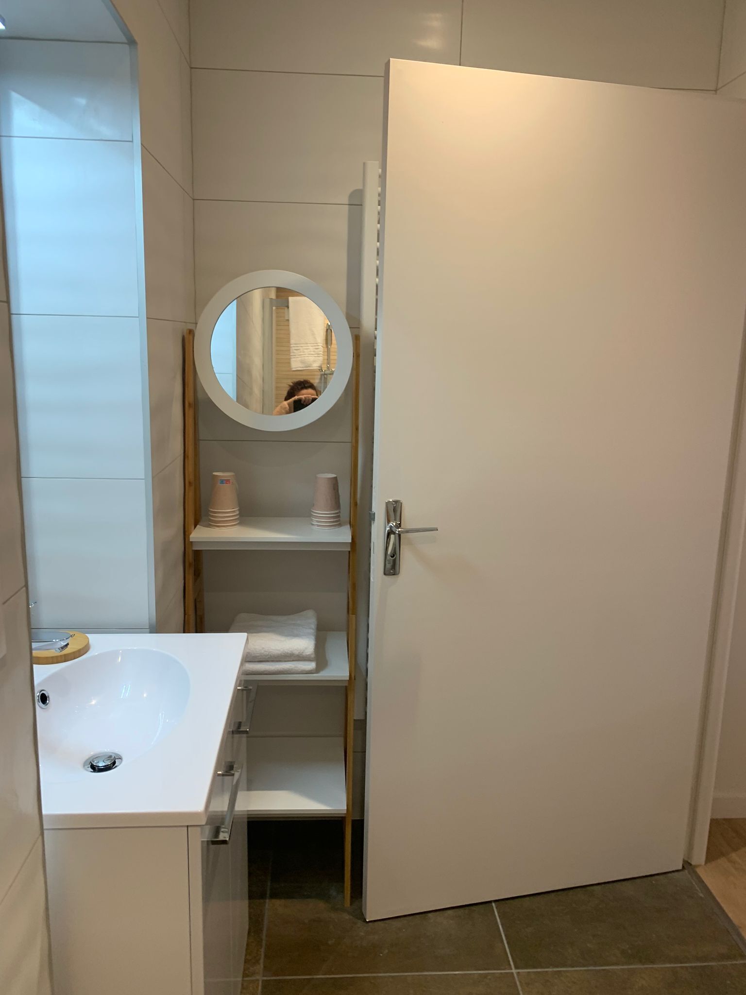 A bathroom with a white sink, a mirror, and a towel rack.