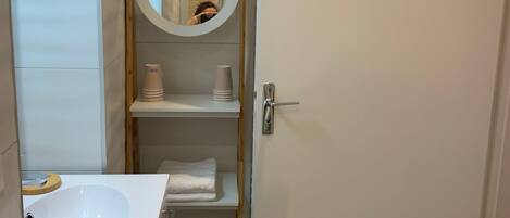 A bathroom with a white sink, a mirror, and a towel rack.