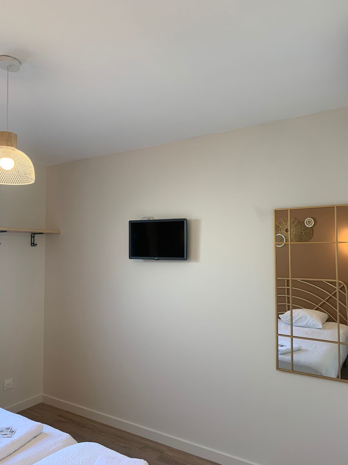 A bedroom with a bed, a television mounted on the wall, and a decorative mirror.