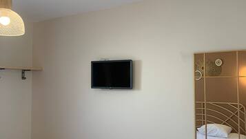 A bedroom with a bed, a television mounted on the wall, and a decorative mirror.