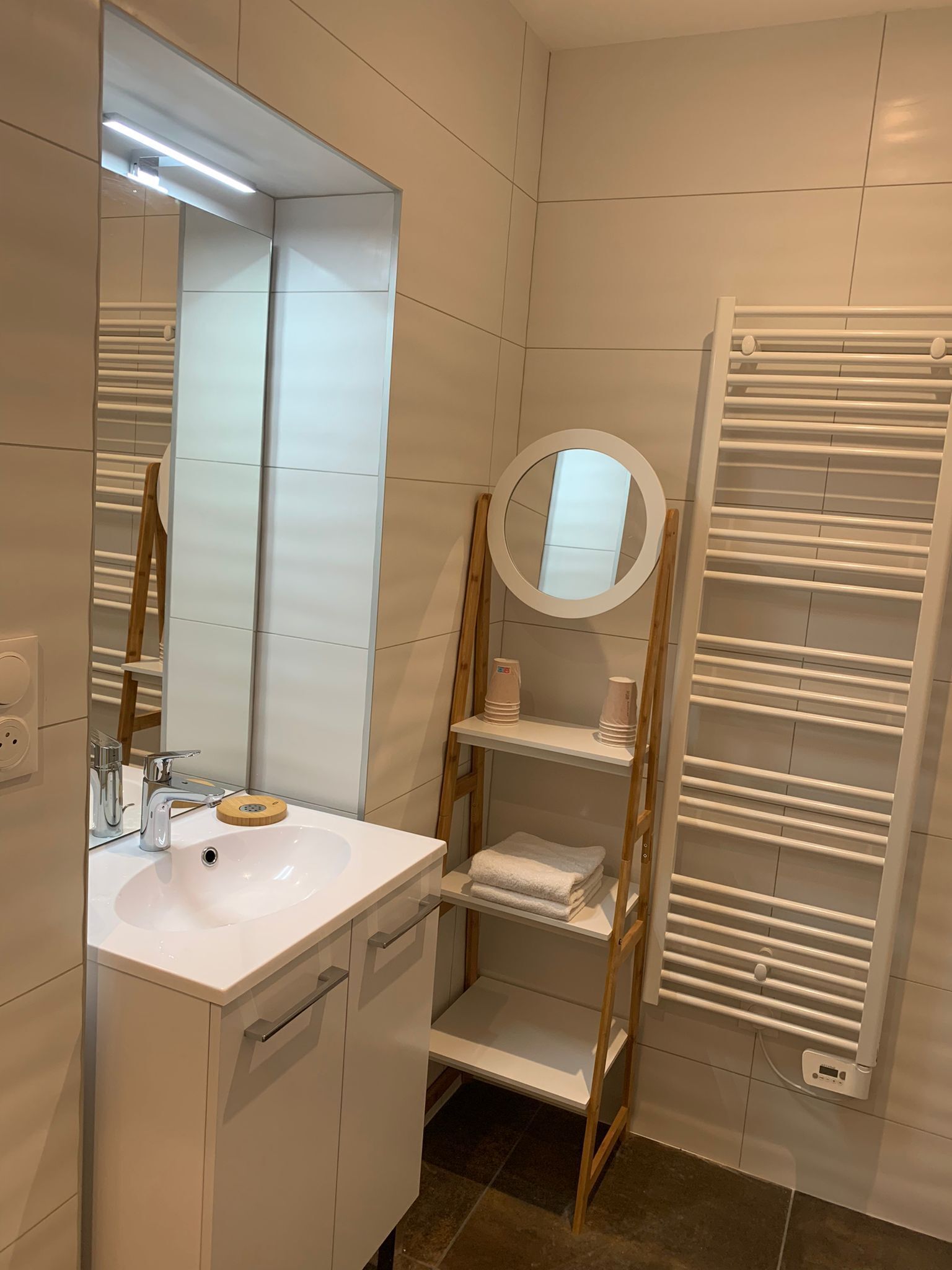 Un baño moderno con lavamanos, espejo y toallero blancos.