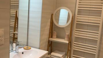 A modern bathroom with a white sink, mirror, and towel rack.