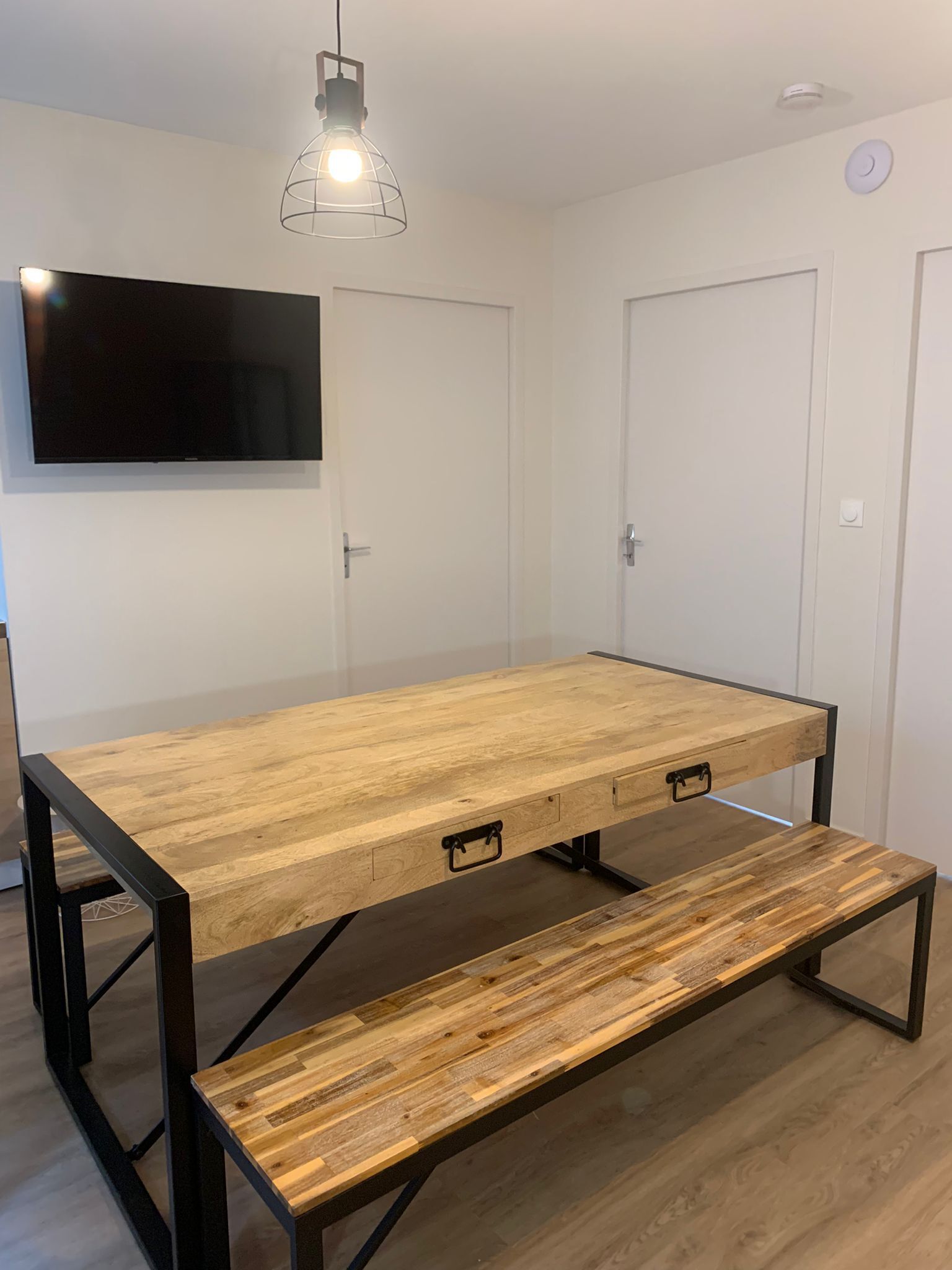 A room with a wooden table, bench, and a mounted TV.