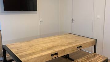 A room with a wooden table, bench, and a mounted TV.