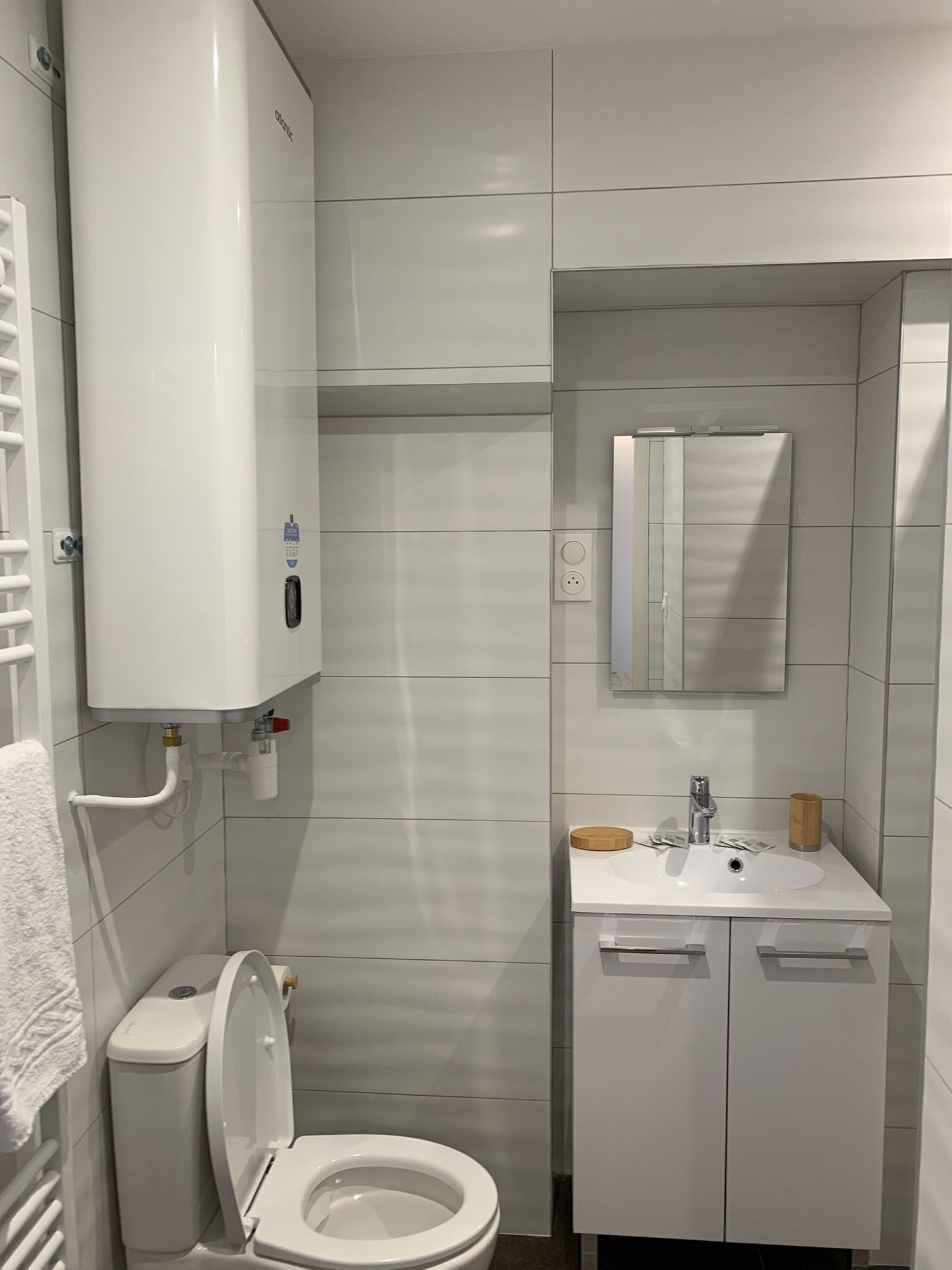 A modern bathroom with a toilet, sink, and mirror.