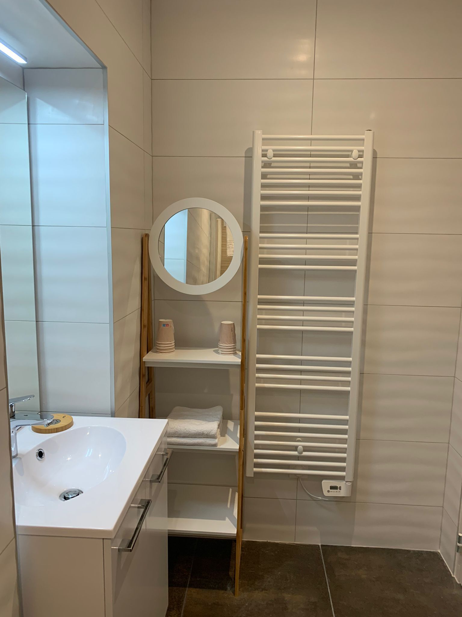 Un baño moderno con lavamanos, espejo y toallero blancos.