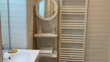 Un baño moderno con lavamanos, espejo y toallero blancos.