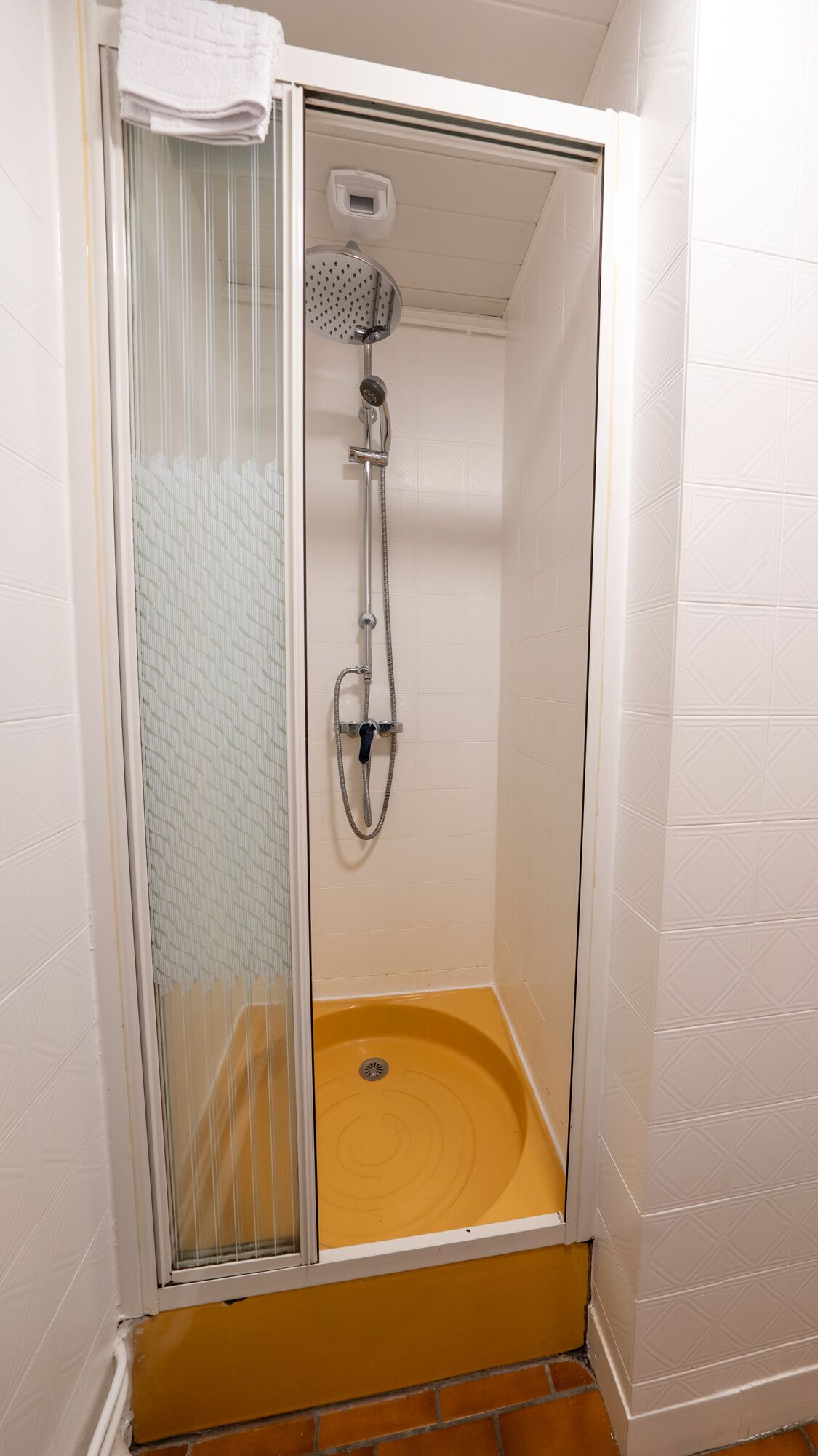 A walk-in shower with a glass door, a showerhead, and a handheld shower attachment.
