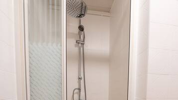 A walk-in shower with a glass door, a showerhead, and a handheld shower attachment.
