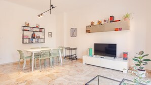 A modern living room with a dining area, a flat-screen TV, and bookshelves. - Residenza Ponte Pietra (Verona)