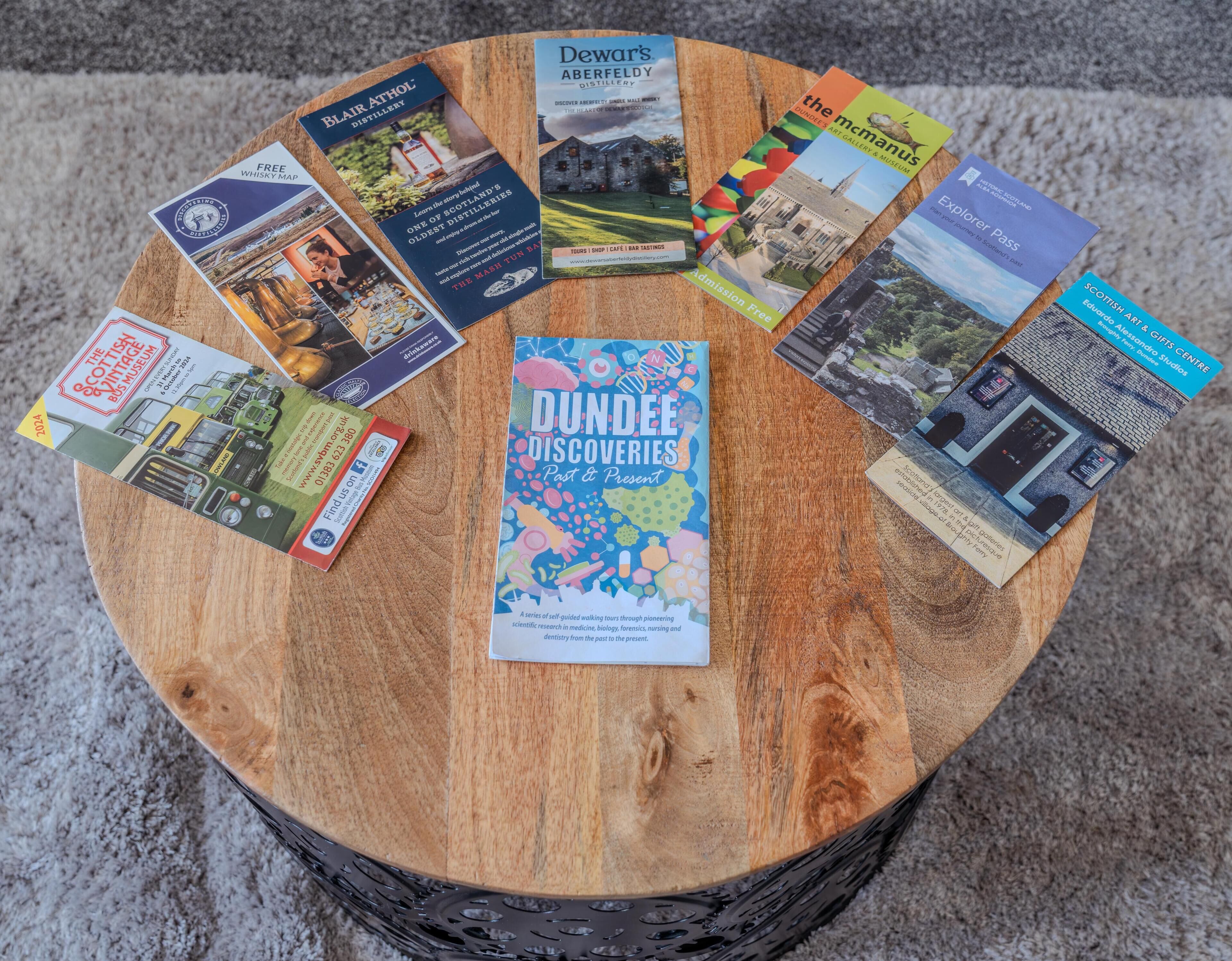 A collection of brochures and a book on a wooden table.